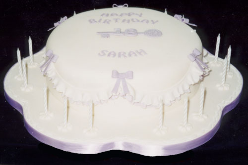 An 18th celebration chocolate cake with sugar-crafted key, bows and candle holders.