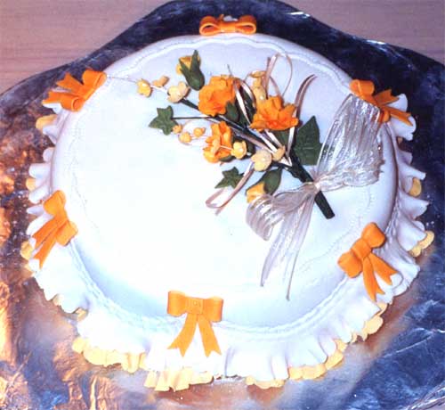 A Golden Anniversary cake with spray of yellow and cream sugar crafted flowers and bows.
