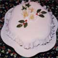 A Christmas cake decorated with holly and Christmas roses.