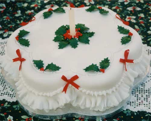 A Christmas cake decorated with sugar crafted holly and frills.