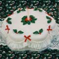 A Christmas cake decorated with sugar crafted holly and frills.