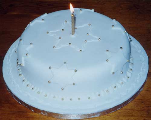 A simple Christmas cake design with sugar stars and gold candle.